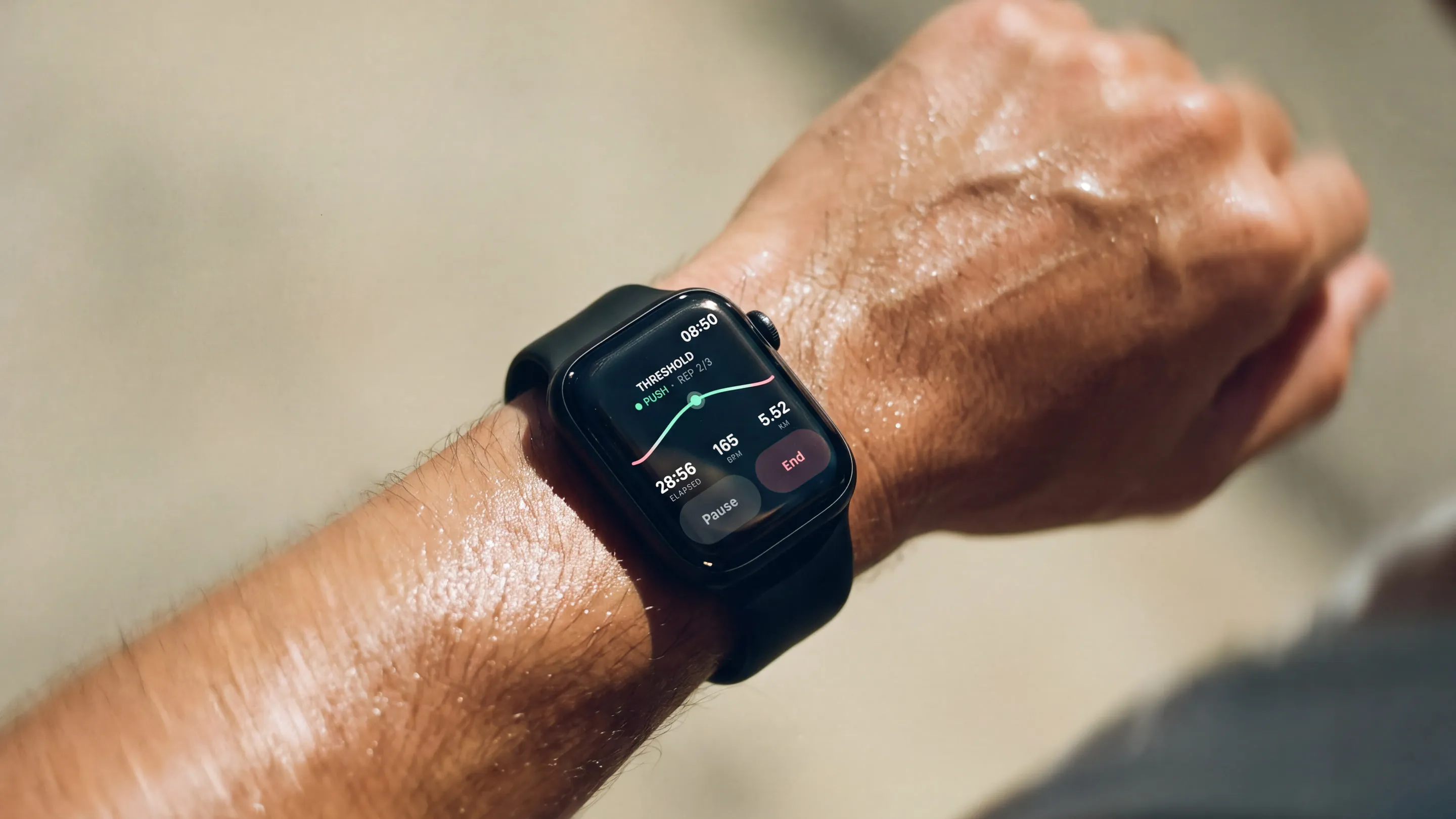 Close-up of a runner's wrist with the Apsia watch showing a threshold run: push, in mint, 165 bpm