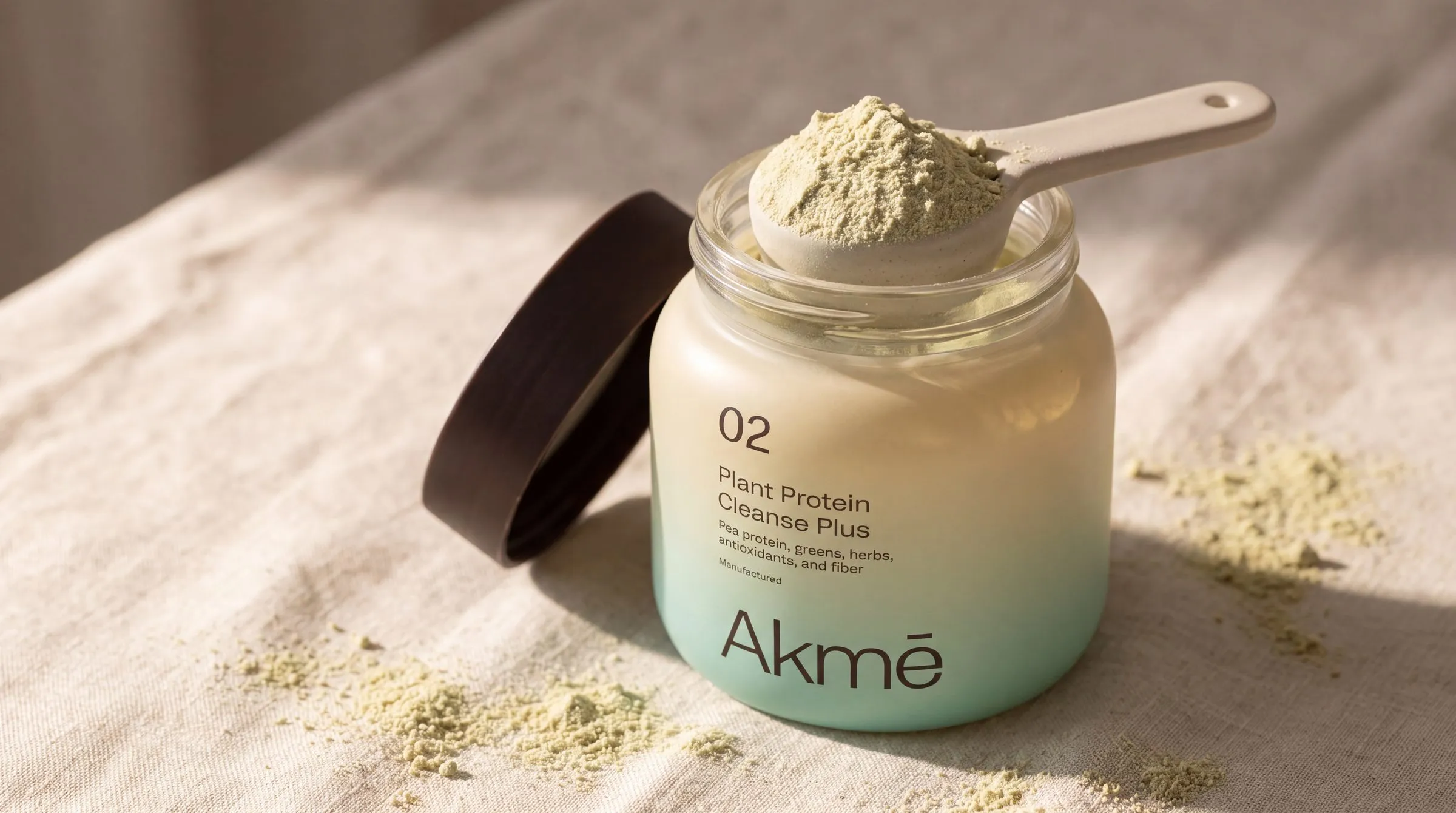 Open jar of 02 Plant Protein with a scoop of green powder on linen